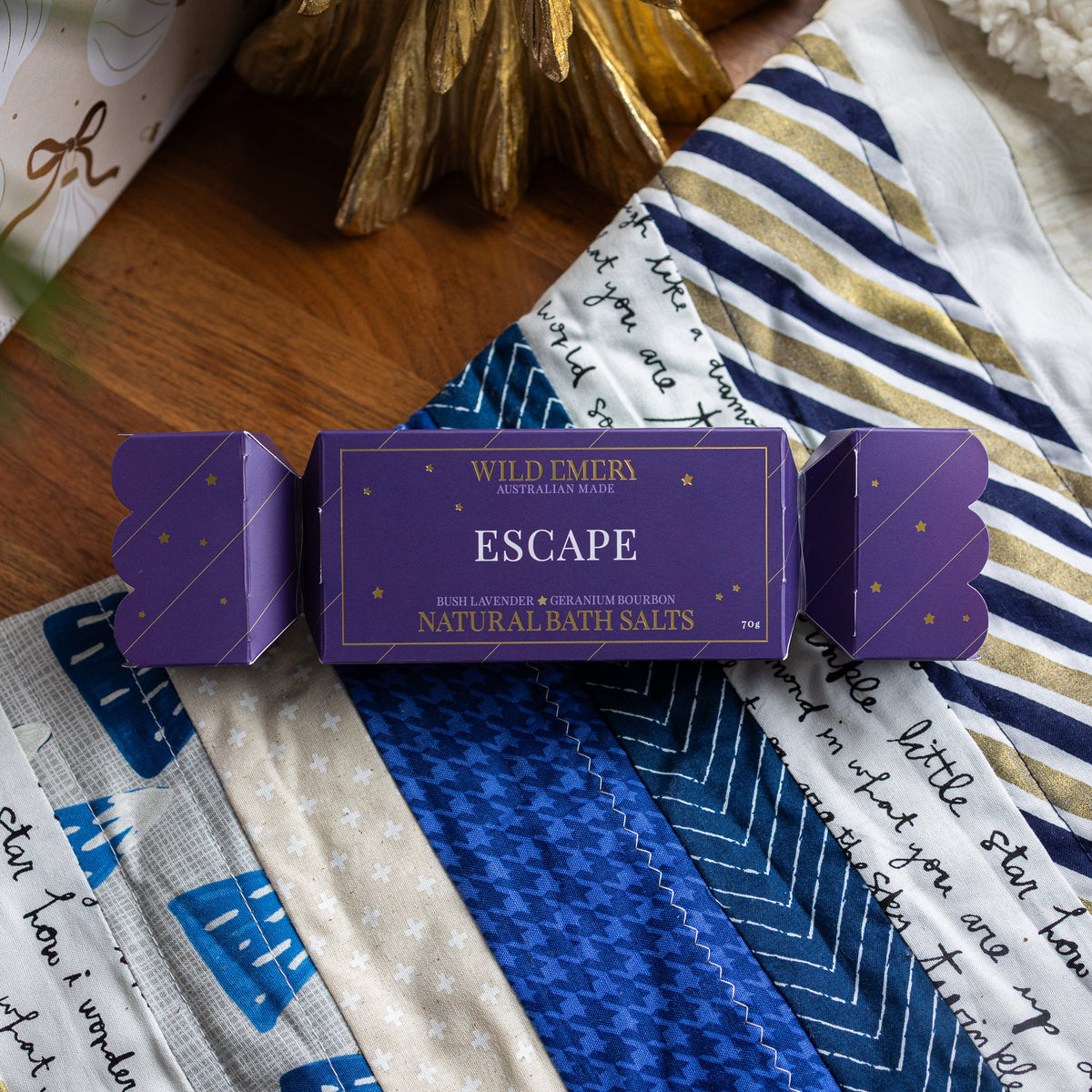 Purple Escape bath salt bon bon, shaped like a Christmas cracker, on a patchwork quilt.