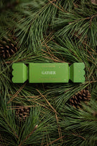 The Gather bon bon on a bed of pine needles and pine cones.