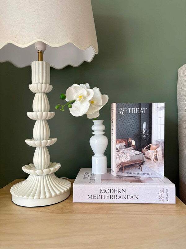 Retreat book box styled on a bedside table with a cream lamp and white orchid