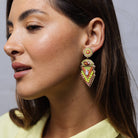 A model wearing a beaded statement earring: a round stud above a stacked arrow drop in lime, coral and pink beads with sparkly stones.