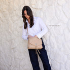 The biscuit bag worn across the body, with a label pointing to its top zip pocket.