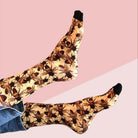 Two legs crossed at the ankle against a dusty pink and cream backdrop, wearing the golden honeybee socks.