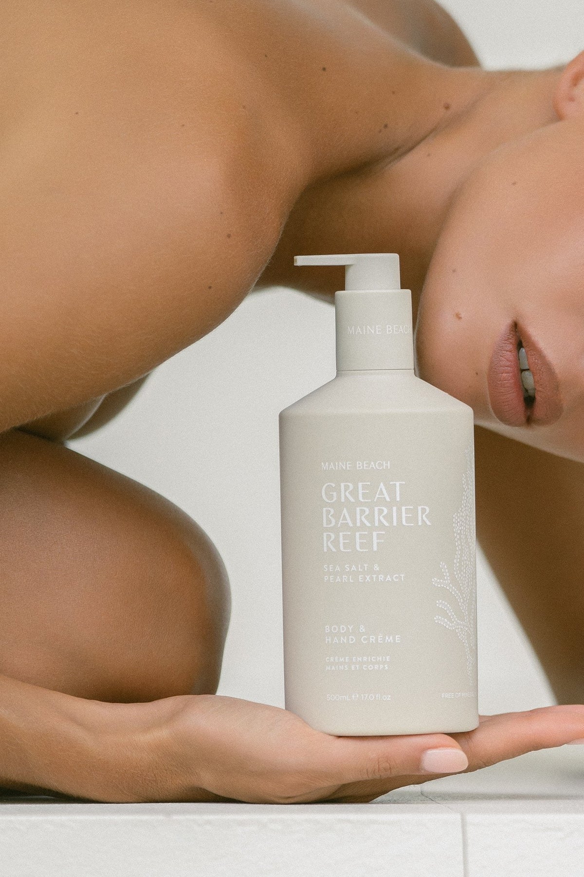 The Great Barrier Reef body and hand creme bottle held up on a hand, its label facing out.