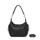 The black bag on its shoulder strap, with the long black cross body strap coiled beside it.