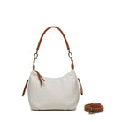The white bag on its tan shoulder strap, with the long tan cross body strap coiled beside it.