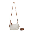 The white bag on its long tan cross body strap, with the patterned cotton strap coiled beside it.