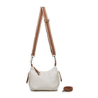 The white bag on a tan and cream patterned cotton strap, with the tan strap coiled beside it.