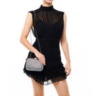 Model in a black mini dress with a sheer yoke wearing the crystal clutch on its silver chain