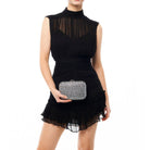 Model in the black mini dress holding the crystal clutch in front of her