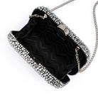 The clutch open, showing a black zigzag-patterned lining and the silver chain clipped inside