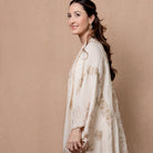 Cream garland cover-up worn over a pale dress
