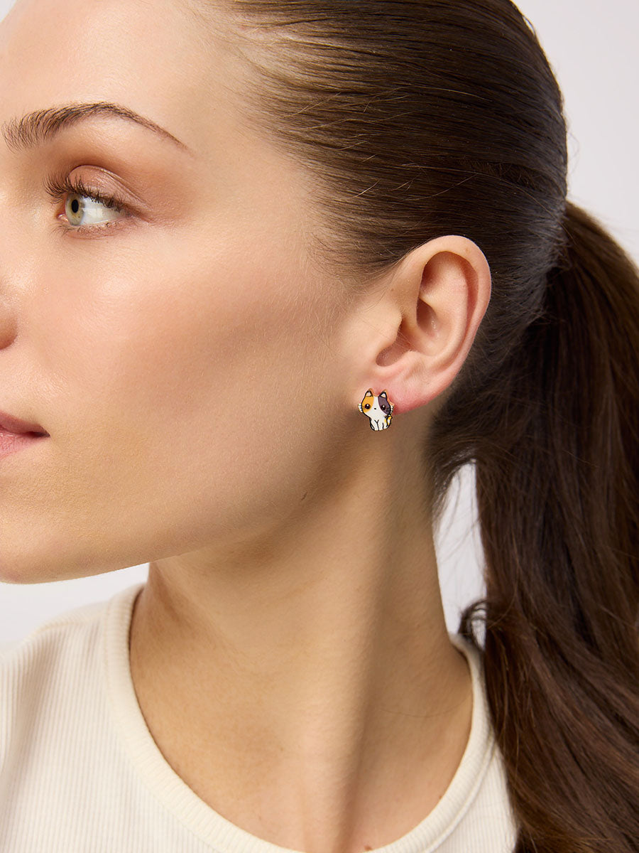 Model with a ponytail wearing a small white, brown and ginger cat stud