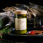 Cedar & Saffron candle on a dark plate with saffron threads, cinnamon, driftwood and red berries