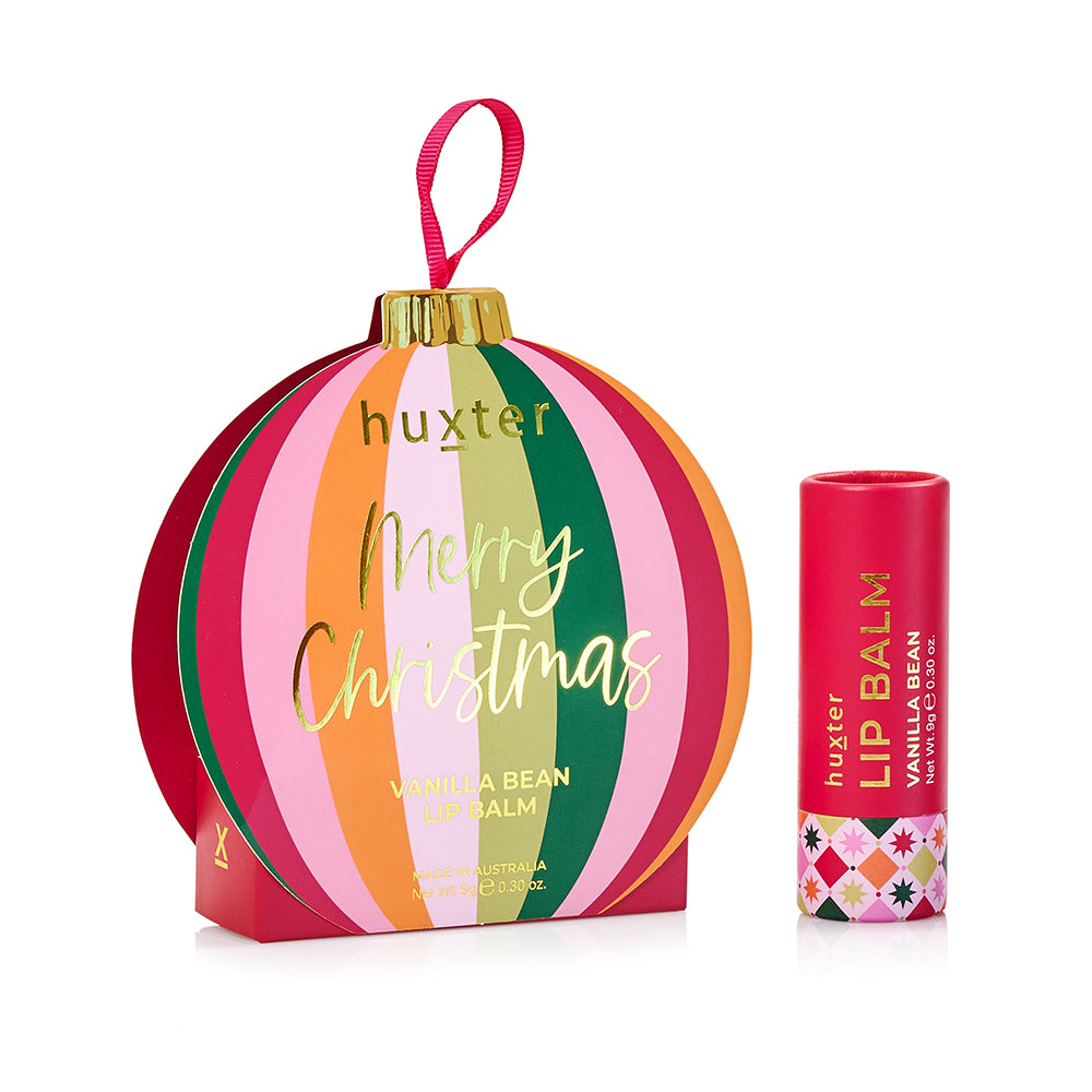 Huxter Vanilla Bean lip balm in a round bauble box with pink, green, orange and red stripes, Merry Christmas in gold, beside the red balm tube.
