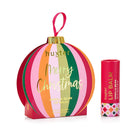 Huxter Vanilla Bean lip balm in a round bauble box with pink, green, orange and red stripes, Merry Christmas in gold, beside the red balm tube.