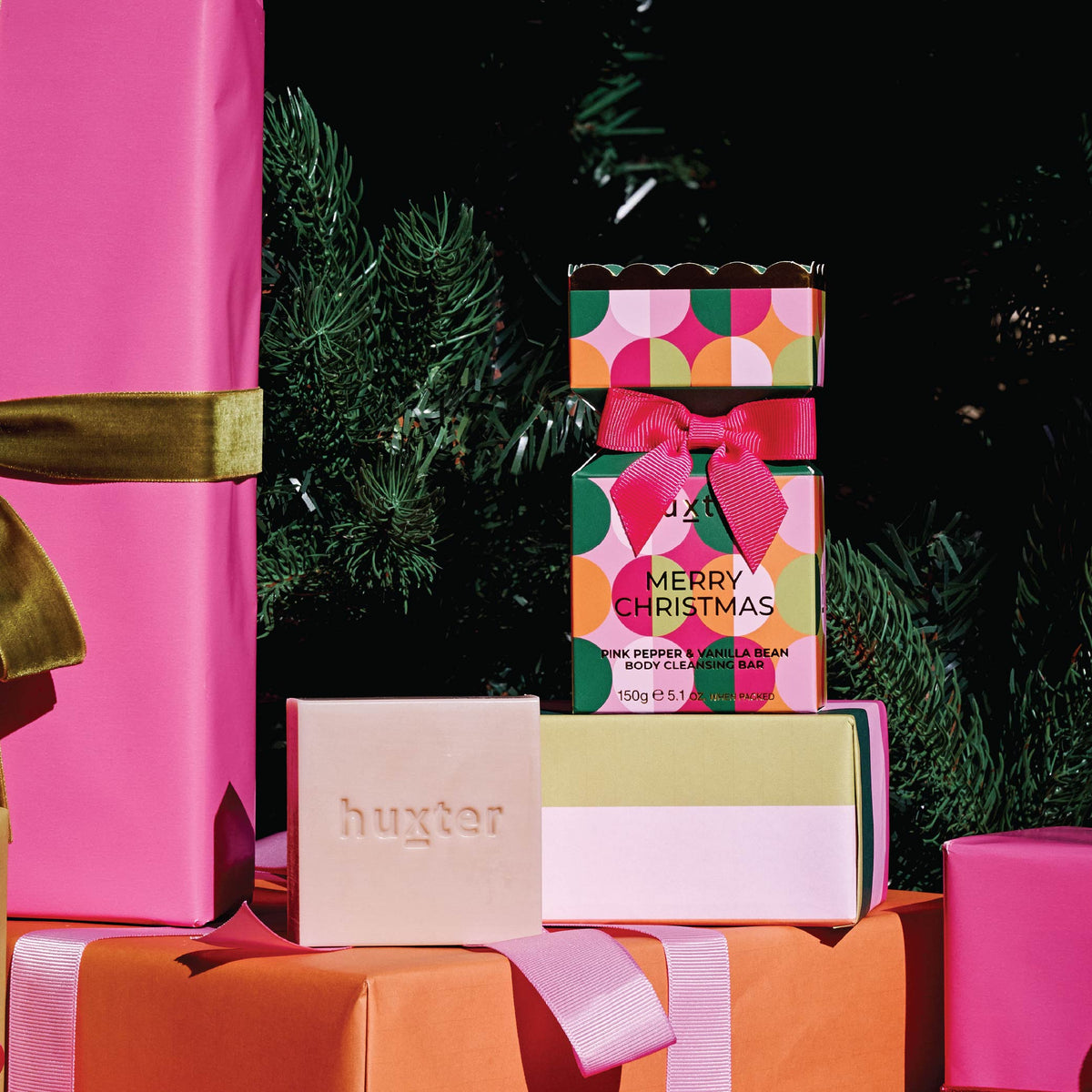 The Circles bon bon cleansing bar box and bar on wrapped presents under a Christmas tree.