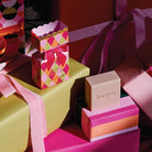 The Diamonds bon bon cleansing bar box and bar on wrapped presents with pink ribbon.