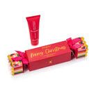 Red Huxter Christmas cracker box printed Merry Christmas in gold, tied with pink ribbon, with the red 50 mL hand balm tube.