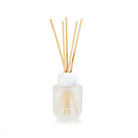 Frosted glass Huxter reed diffuser bottle with a round white top and five natural reeds.
