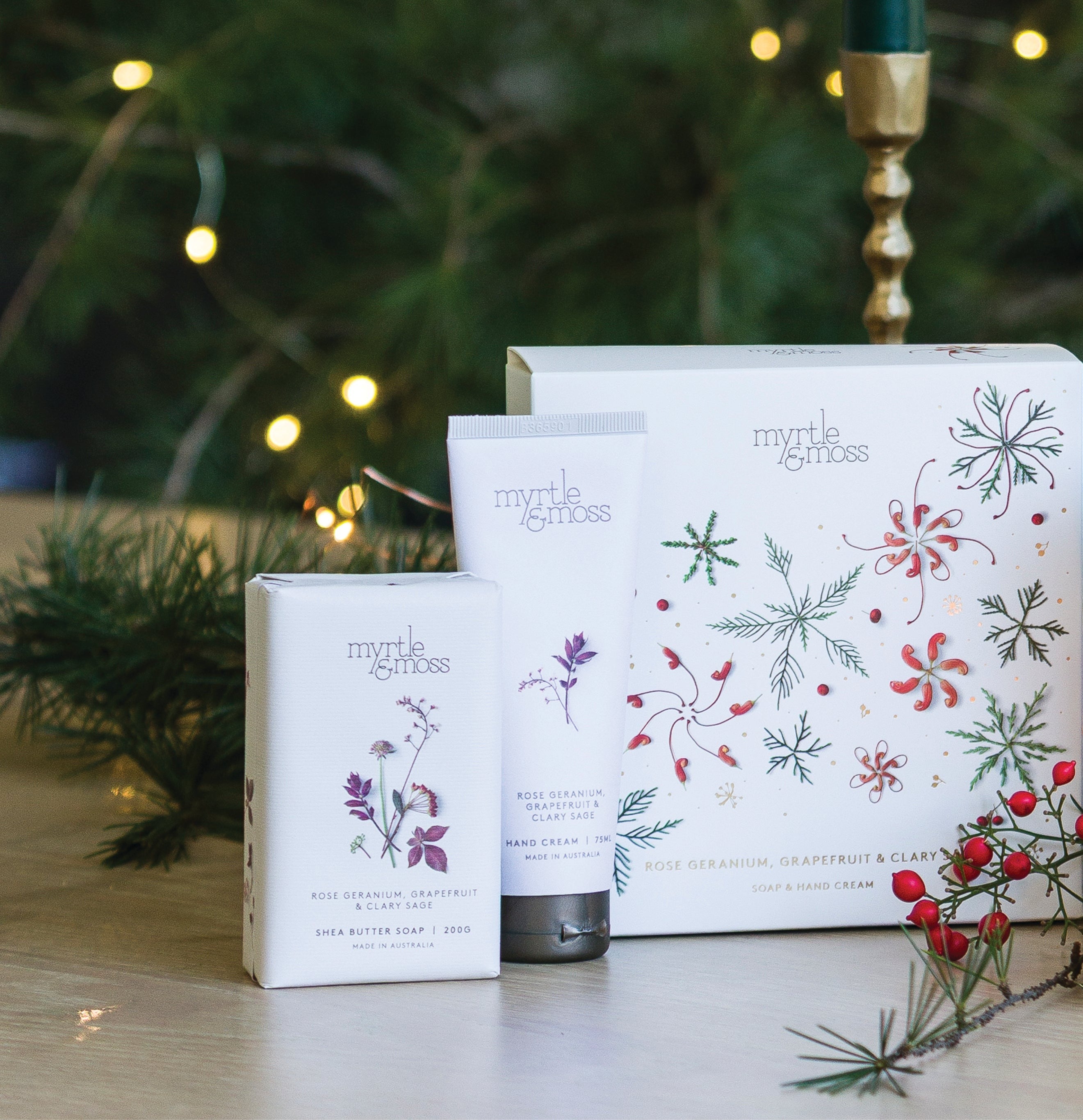 Myrtle & Moss Rose Geranium Christmas gift box printed with green snowflakes and coral native flowers, with its wrapped shea butter soap and 75 mL hand cream in front.