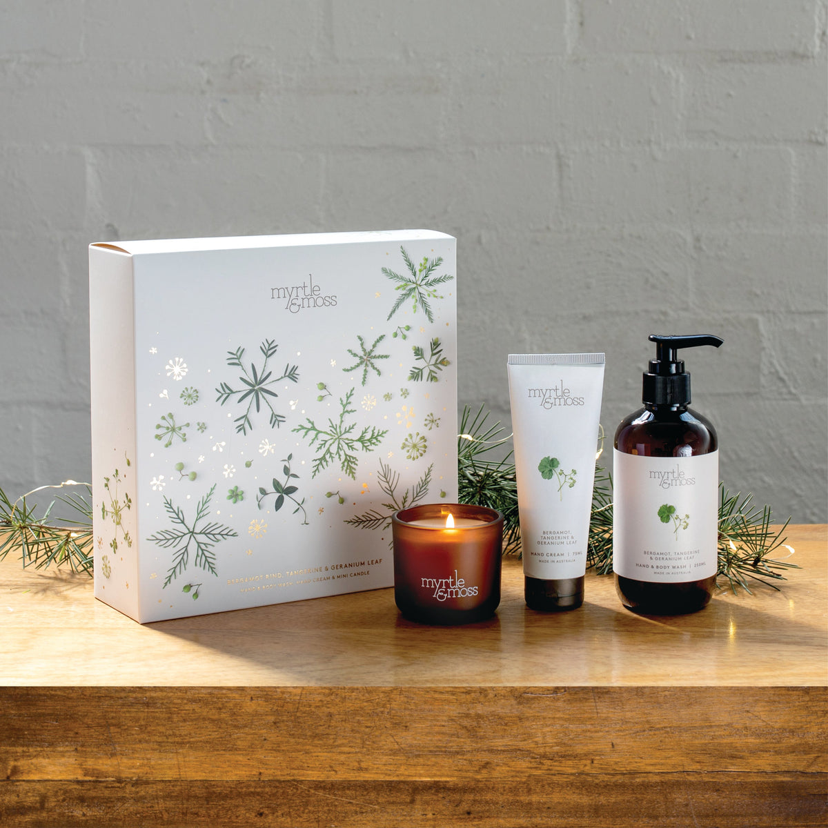Myrtle & Moss Bergamot Christmas gift box with the mini candle, 75 mL hand cream and 250 mL amber pump bottle of hand and body wash in front.