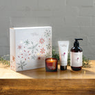 Myrtle & Moss Rose Geranium Christmas gift box with the mini candle, 75 mL hand cream and 250 mL amber pump bottle of hand and body wash in front.