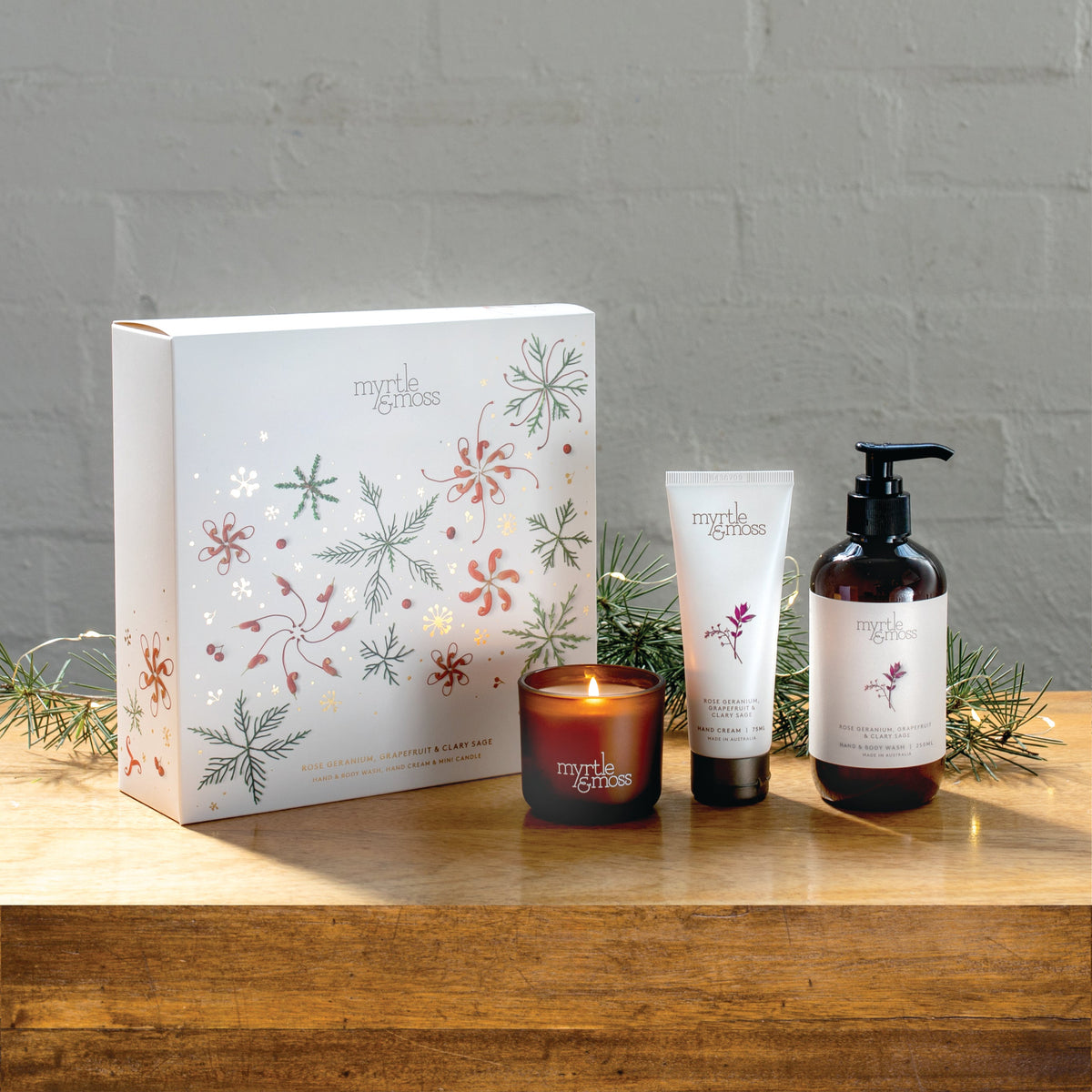 Myrtle & Moss Rose Geranium Christmas gift box with the mini candle, 75 mL hand cream and 250 mL amber pump bottle of hand and body wash in front.