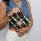 A model holding the beaded coffee and croissant clutch against a denim top.