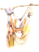 Apricot Watercolour cotton viscose scarf knotted over a branch, watercolour blooms in cream, apricot and yellow