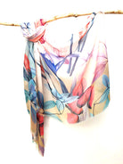 Coral and Teal Floral cotton viscose scarf knotted over a branch, coral, teal and blue painted flowers on a white to sand ground