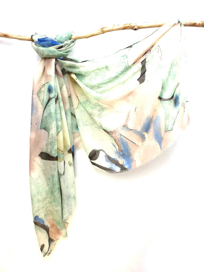 Mint Watercolour cotton viscose scarf knotted over a branch, mint and peach print with blue washes and frayed ends
