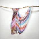 Pastel Stripe cotton viscose scarf knotted over a branch, painted stripes in lilac, sky blue, coral, peach and caramel