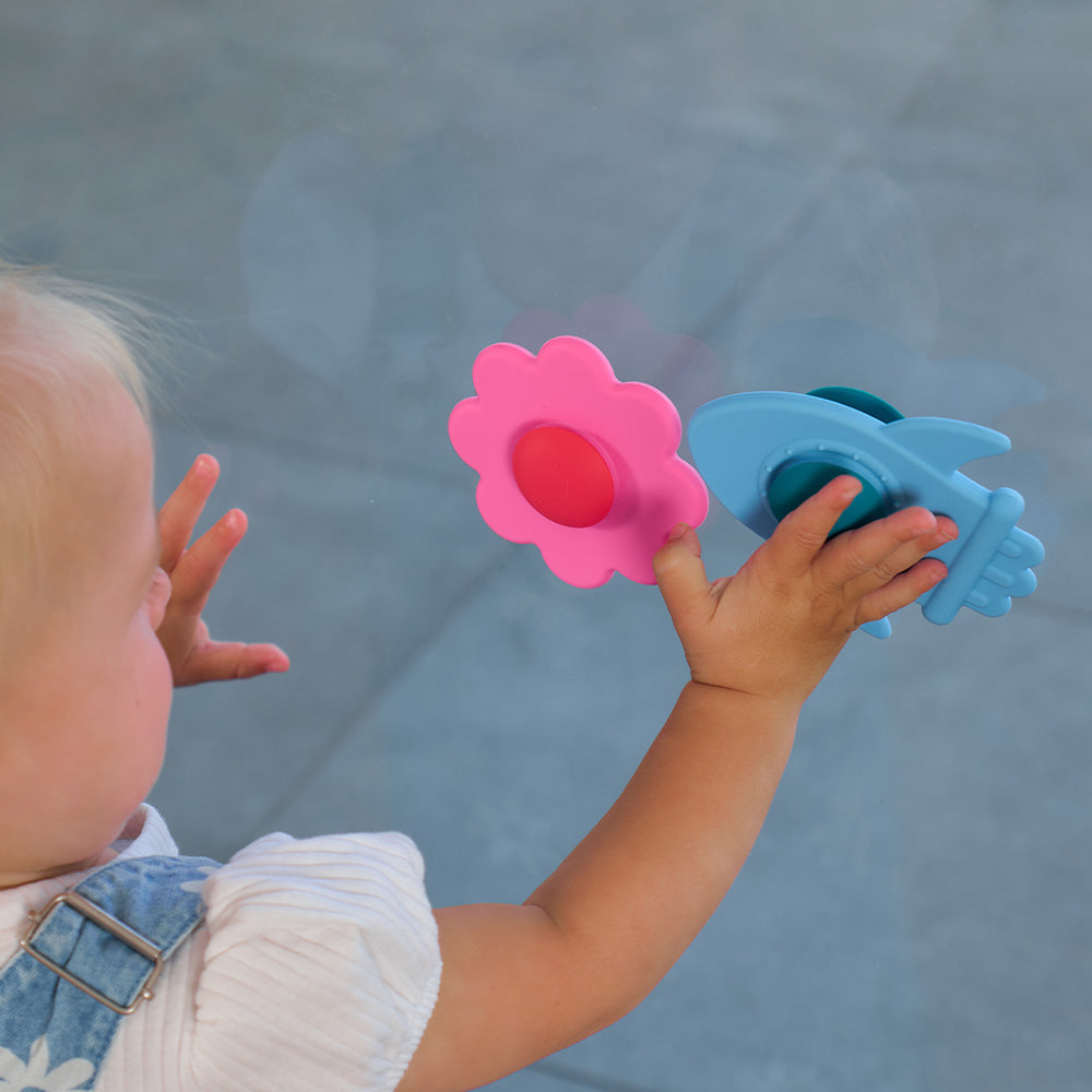 Toddler holding a pink daisy spinner and a blue rocket spinner