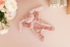The petal pink bunny comforter lying on a pink surface beside fresh flowers.