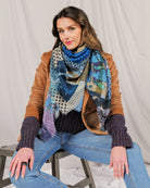 Model in a tan leather jacket wearing the blue patchwork print scarf knotted at the neck