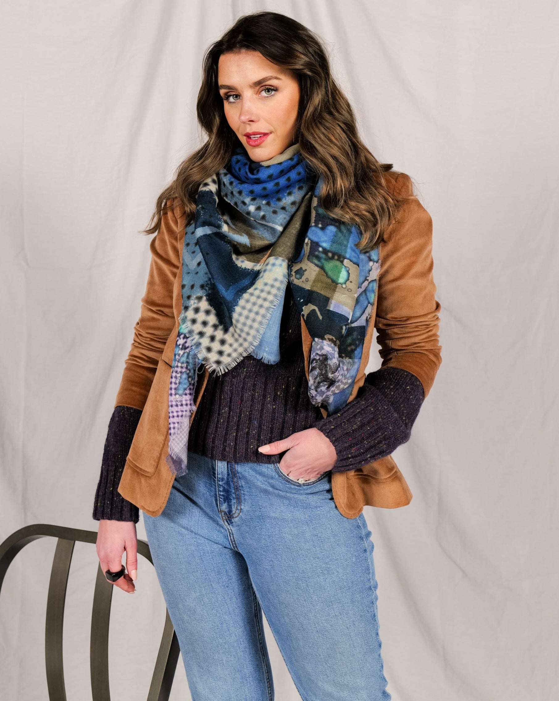 Close view of the scarf draped over a tan jacket and navy knit