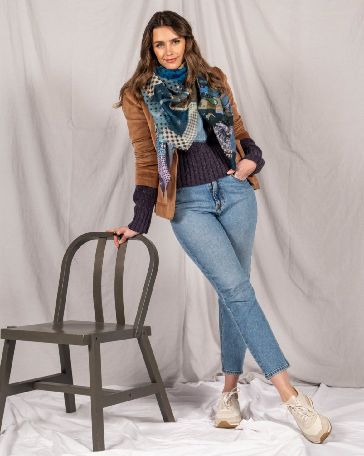Model standing beside a chair with the scarf tied loosely over a navy jumper