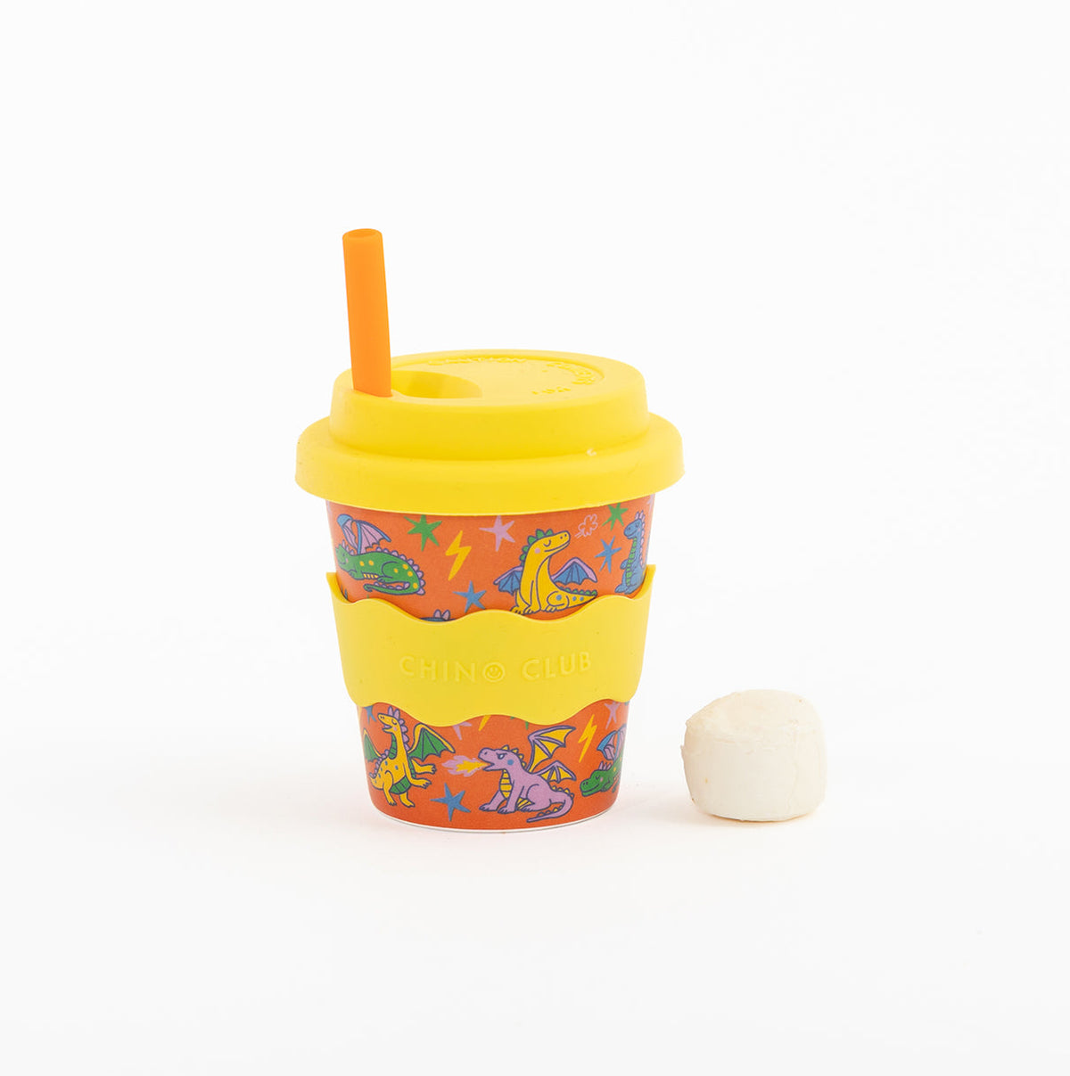 Dragons babychino cup: orange dragon print with a yellow lid and wavy sleeve, an orange straw and a marshmallow beside it