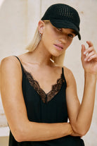 Model in a black lace-trimmed camisole, hand raised beside the Black crochet cap