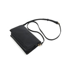 The black bag lying at an angle with the slim strap looped behind.