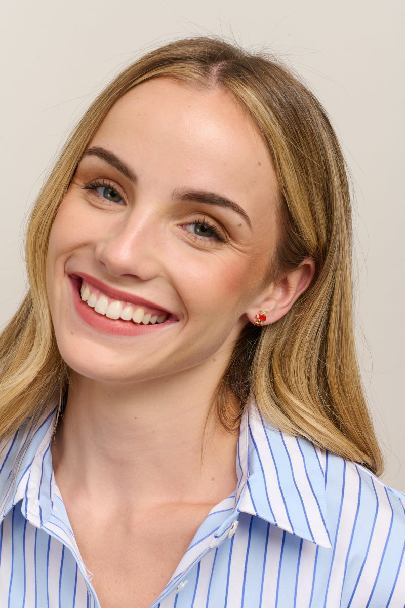 Smiling model in a striped shirt wearing the apple stud earrings