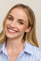 Smiling model in a striped shirt wearing the apple stud earrings