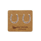 Pair of gold-tone horseshoe stud earrings set with clear cubic zirconia, on an Ear Mints card.