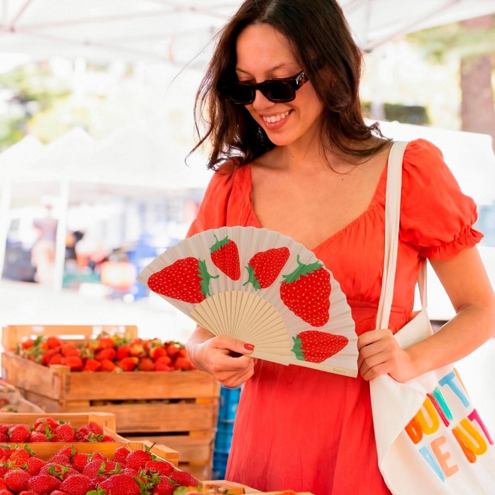 Woman at a strawberry stall holding the open strawberry fan