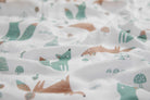 Close-up of the print: sage and terracotta foxes, small trees and mushrooms on white muslin.