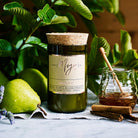 French Pear candle in a reclaimed wine bottle beside pears, honey and cinnamon sticks