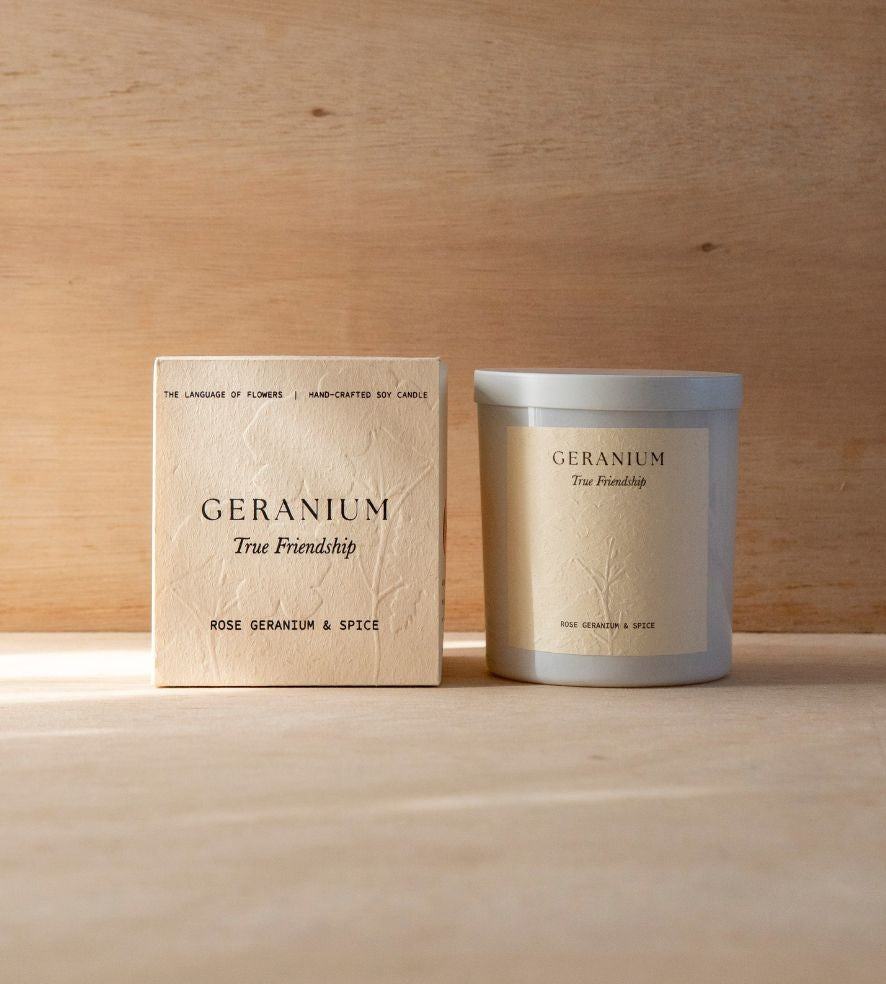 The Geranium candle in its white vessel beside its cream box.