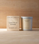 The Geranium candle in its white vessel beside its cream box.