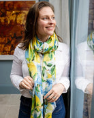 Woman in a white shirt and jeans wearing the lemon blossom scarf loosely knotted at her neck.