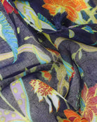 Close-up of the Jade scarf fabric showing orange, yellow and turquoise flowers on navy with a tassel.